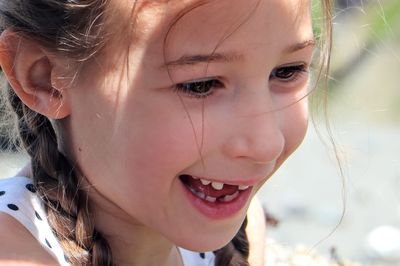 Close-up of cute toothless smiling little girl with braids 