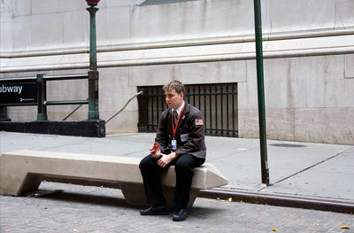 Full length of young man using mobile phone while sitting outdoors