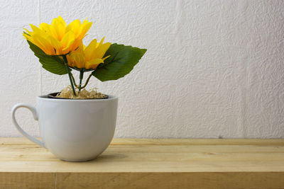 Close-up of flower vase on table against wall