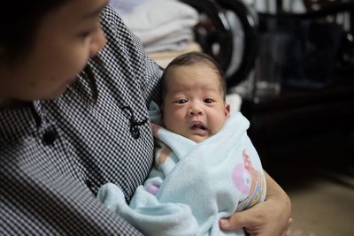 Close-up of woman carrying baby at home