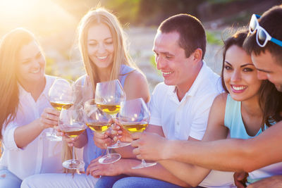 Happy friends raising toast outdoors