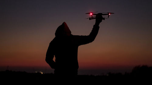 Silhouette man standing on field against sky during sunset