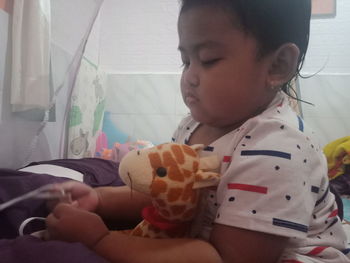 Cute baby boy sitting on bed at home