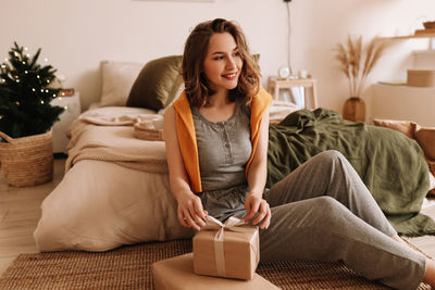 A pretty girl in pajamas rejoices and smiles in the christmas holidays in a cozy bedroom interior