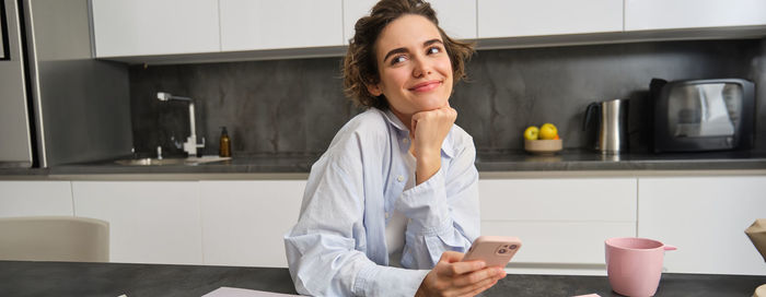 Portrait of young woman standing at home