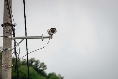 Low angle view of security camera against sky