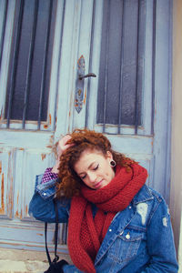 Young woman sitting against closed door