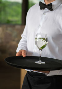 Waiter brings a glass of wine to a black tray