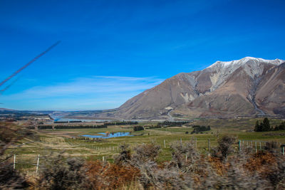 Scenic view of landscape and mountains against blue sky