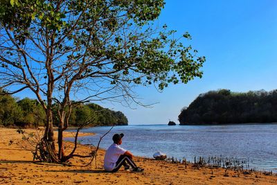 Woman sitting on beach against sky