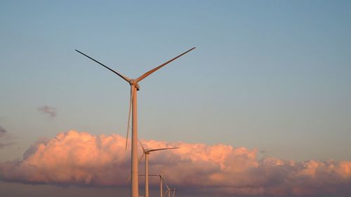 Wind turbines against sky during sunset