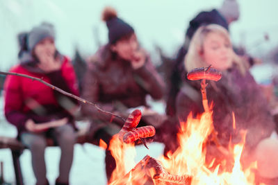 Friends preparing food over campfire