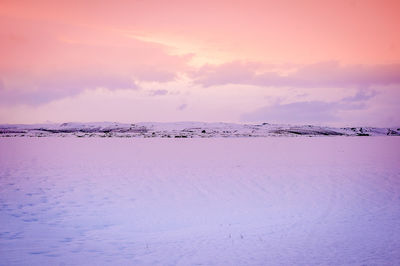 Scenic view of snow covered land against sky during sunset