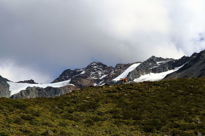 Scenic view of mountains against cloudy sky during winter