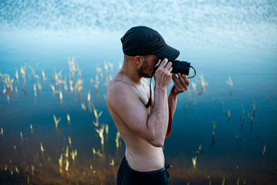 Young man photographing against sky