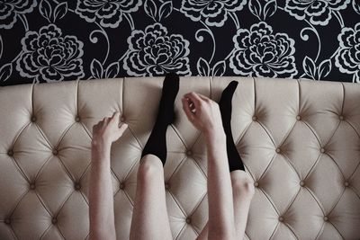 Low section of woman wearing black socks while sitting on sofa at home