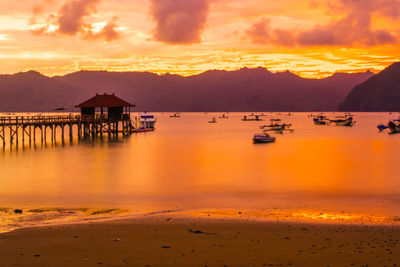 A wooden pier stretches out into a calm bay at sunset, near trenggalek, east java, indonesia.