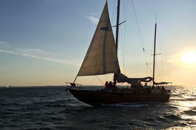 Sailboat sailing on sea against sky during sunset