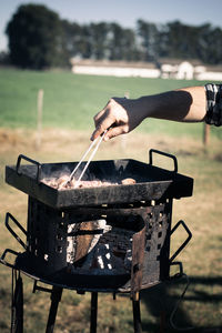 Man preparing food on barbecue grill at field