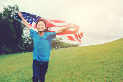 Girl holding american flag while running on field
