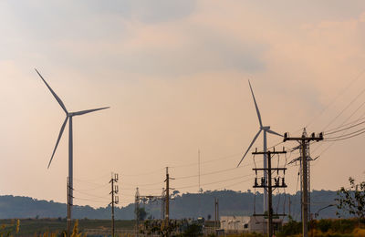 Wind turbines against sky during sunset