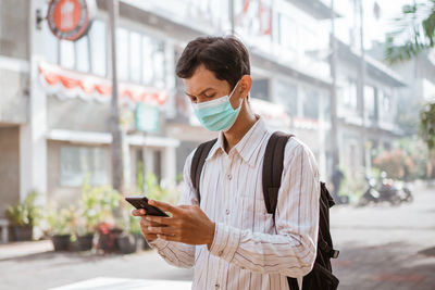 Young man using mobile phone in city