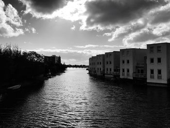 Canal amidst buildings in city against sky