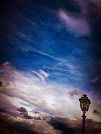 Low angle view of illuminated street light against cloudy sky