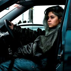 Side view of young woman driving car