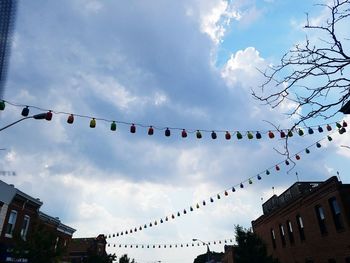 Low angle view of lanterns hanging in city against cloudy sky