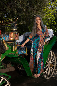 Sensuous woman standing in carriage against trees