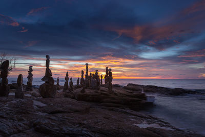 Silhouette rocks on beach against sky during sunset