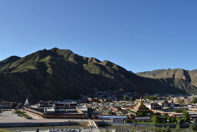 Scenic view of buildings and mountains against clear blue sky