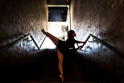 Full length of ballet dancer with legs apart standing on floor