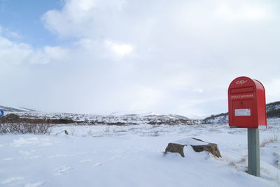 Road sign on snow against sky