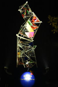 Low angle view of illuminated lighting equipment against black background