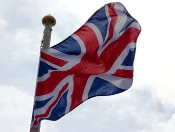 Low angle view of british flag waving against cloudy sky