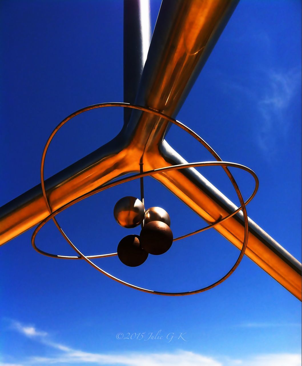 low angle view, sky, blue, lighting equipment, hanging, metal, close-up, electricity, street light, no people, light bulb, circle, outdoors, sunlight, metallic, sphere, electric light, day, part of, cloud