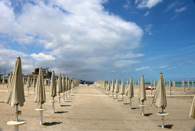 Wooden chairs on beach against sky