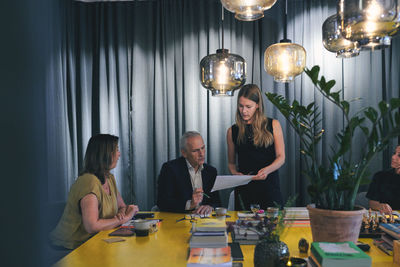 Young businesswoman discussing over document with businessman during meeting in board room