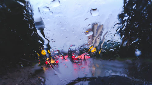 Close-up of wet car window against sky