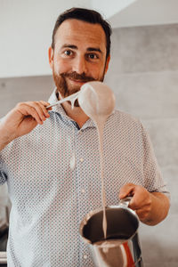 Male chef smiling while preparing dough for pancakes