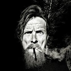 Portrait of man smoking against black background