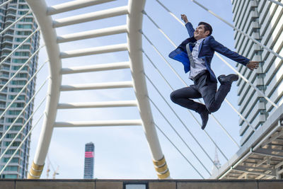 Low angle view of man jumping against building