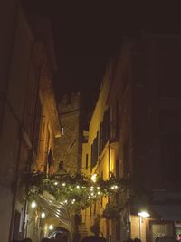 Low angle view of illuminated street amidst buildings at night