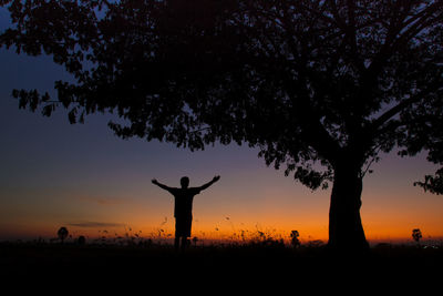 Silhouette man on field against sky at sunset