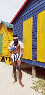 Young man standing by huts at beach