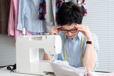 Worried craftswoman sitting with head in hands on table at workshop