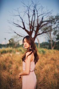 Young woman looking away while standing on field