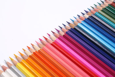 Close-up of colored pencil arranged in a row against white background